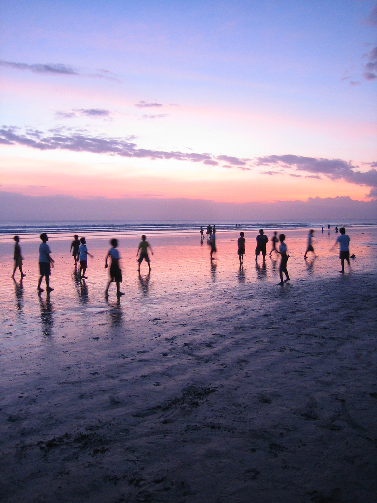 Enfants jouant au football sur la plage au couché du soleil.