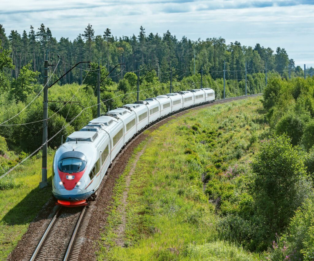 Modern high-speed train approaches to the station at summer morning time.