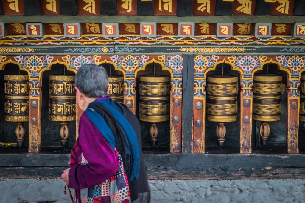 Old woman spinning prayer wheels in Thimphu, Bhutan