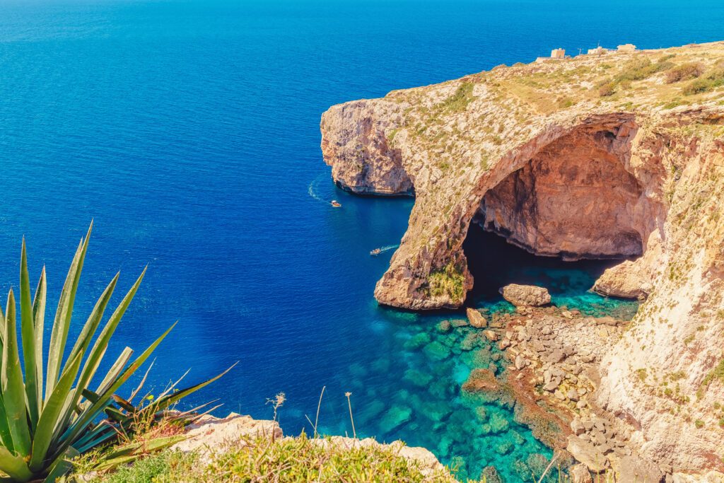 Blue Grotto in Malta. Pleasure boat with tourists runs. Natural arch window in rock