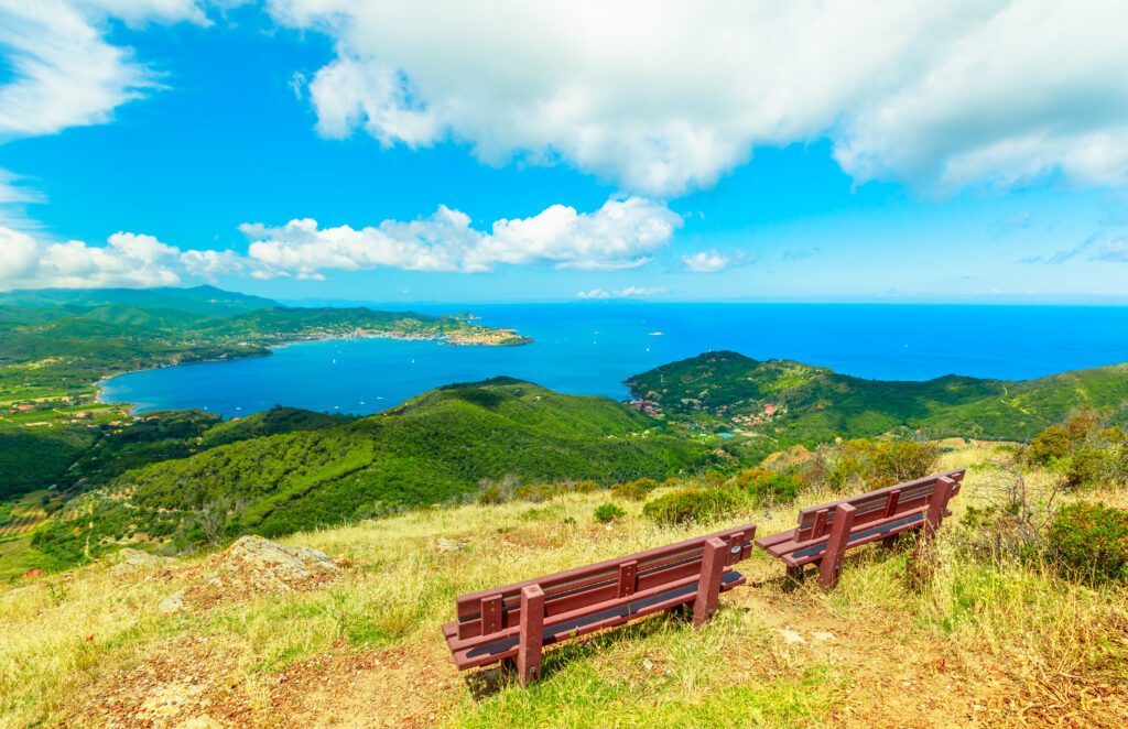 Relax benches to admire panoramic views of Portoferraio Gulf, Elba Island, during hiking to Volterraio Castle. Panoramic landscape of Elba mountains. Travel in Tuscany, Italy destination, Europe.
