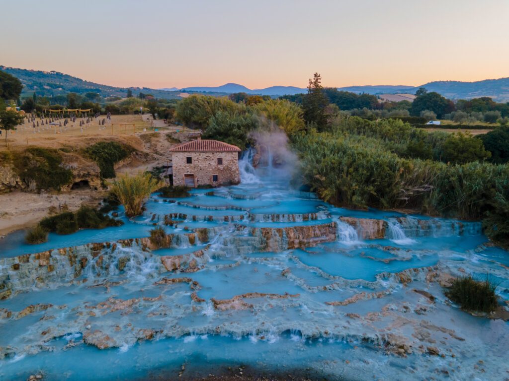 natural spa with waterfalls and hot springs at Saturnia thermal baths, Grosseto, Tuscany, Italy,Hot springs Cascate del Mulino man and woman in hot spring taking a dip during morning with fog