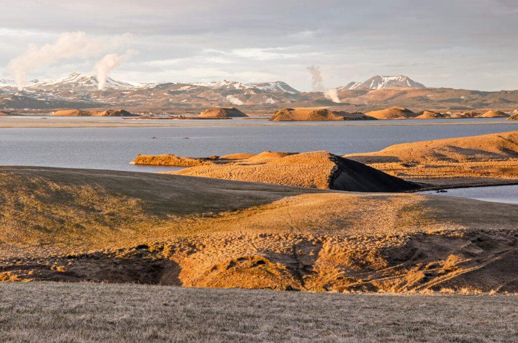 Skútustaðir, Iceland, April 27, 2022: Last rays of the sun illuminate the strange landscape around lake Myvatn, from which plumes of hot steam escape in the distance