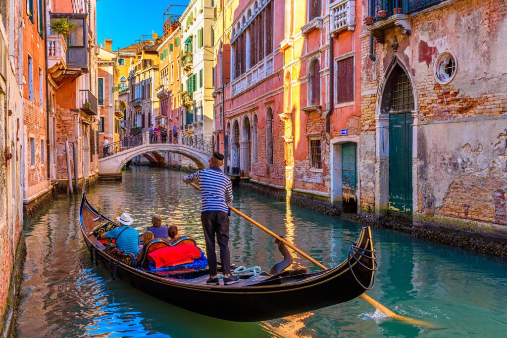 Narrow canal with gondola and bridge in Venice, Italy. Architecture and landmark of Venice. Cozy cityscape of Venice.