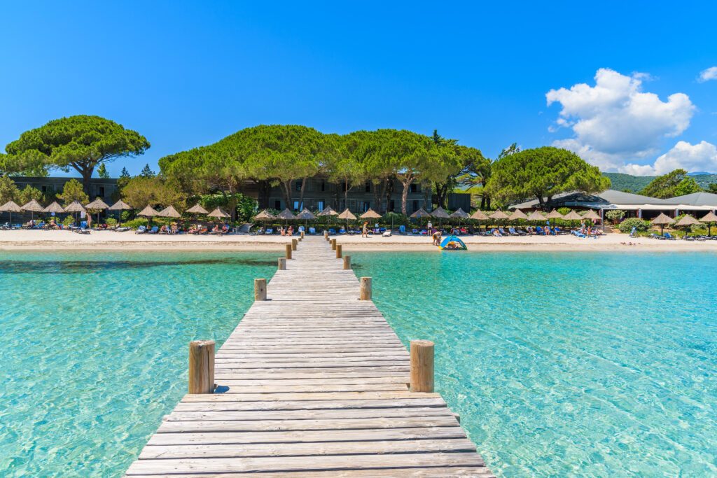 Wooden jetty and turquoise sea water on beautiful Santa Giulia beach, Corsica island, France