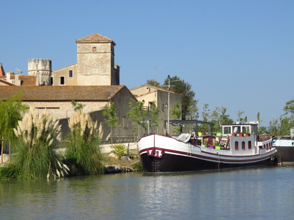 Tourisme fluvial, péniche amarrée sur le canal du Midi, dans le port fluvial du village de Colombiers dans l'Hérault (France)