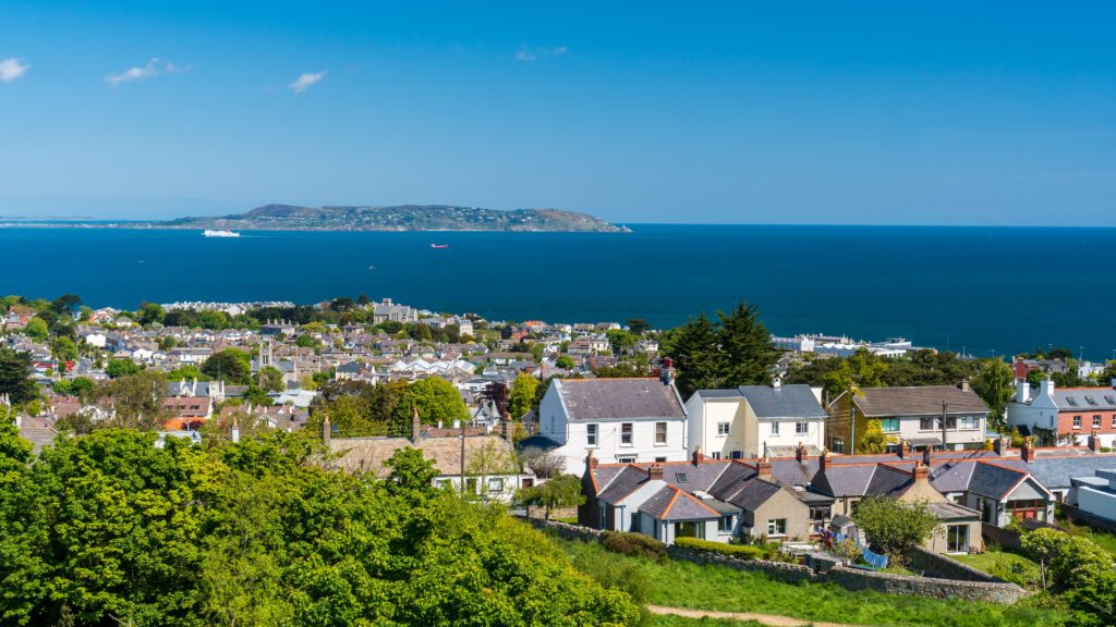 Dalkey village houses as seen from the hill top with the Howth peninsula on the horizon. Sunny summer day in Dublin, Ireland.