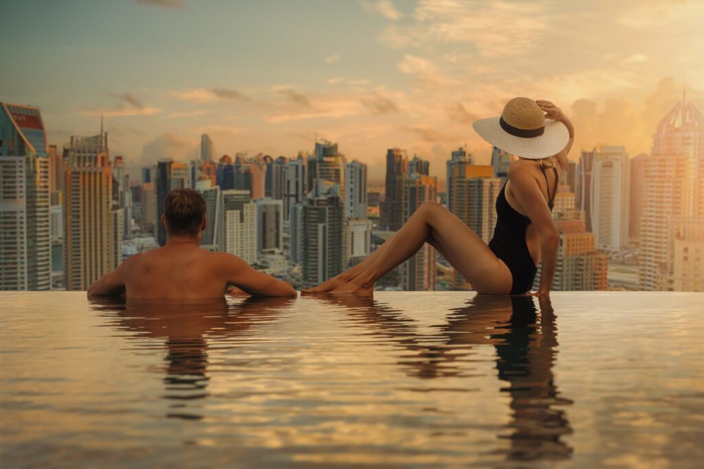 couple enjoying Dubai skyline with skyscrapers architecture from hotel infinity pool at sunset. luxury vacation and travel. United Arab Emirates
