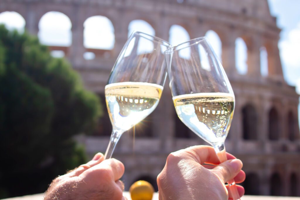 two hands hold a glass of champagne against the backdrop of the Coliseum. Christmas concept Christmas and New Year in Italy