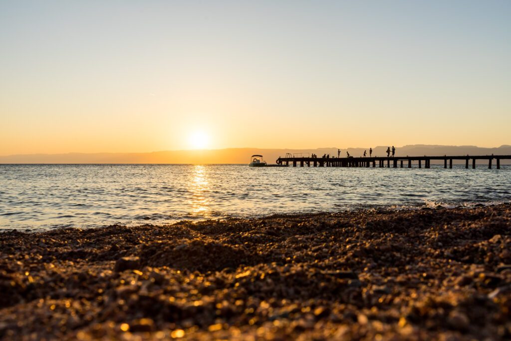 Berenice beach at sunset near Aqaba, Jordan, human silhouettes on the pier at sunset by the red sea