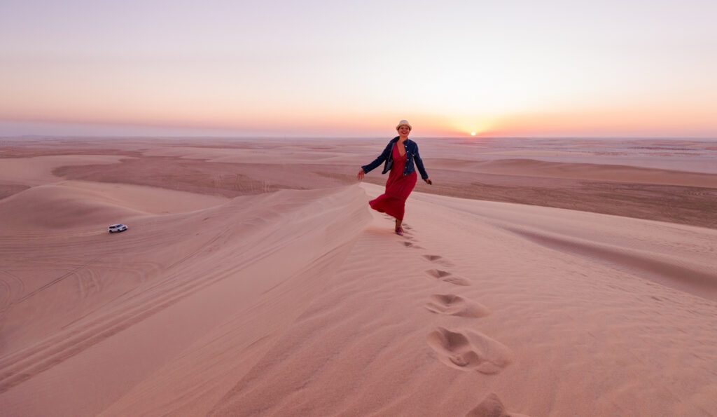 Woman on a hill in the desert at sunset, Qatar