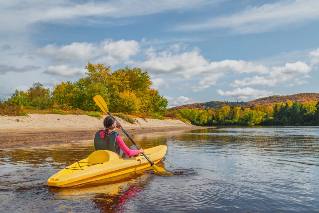 Kayak fun water sports down on river in Laurentians, Quebec. Canada travel destination. Woman kayaker kayaking in Mont-Tremblant during autumn.