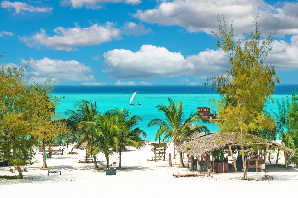 Beautiful tranquil empty bright white paradise sand beach, sun beds, palm trees, bamboo hut bar, turquoise water - Paje, Zanzibar