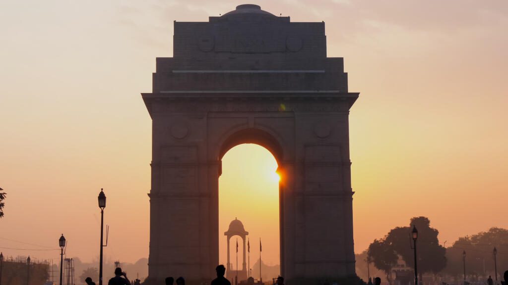 india gate at sunrise with sun lens flare at new delhi