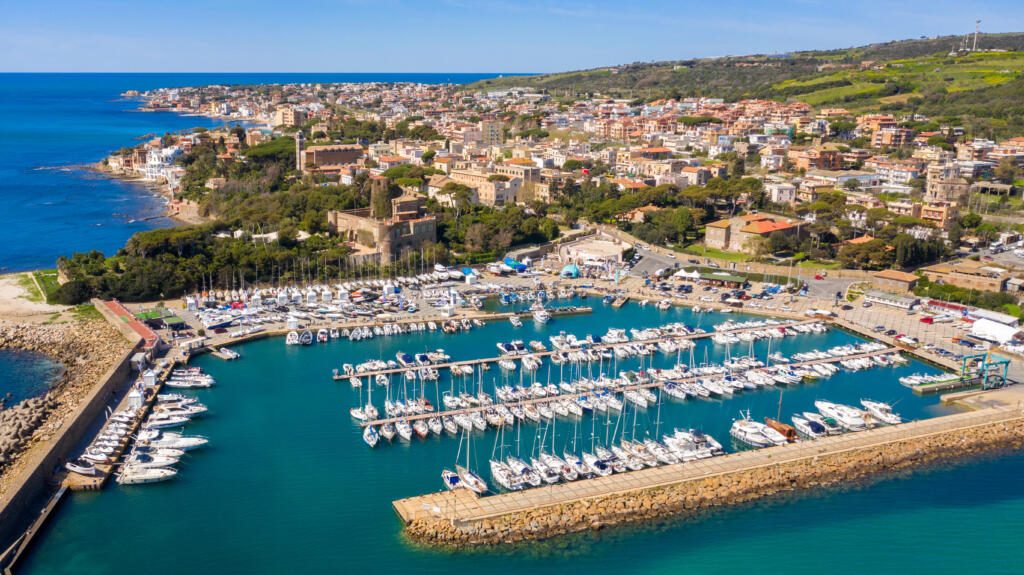 Aerial view of the marina and port of Santa Marinella, in the Metropolitan City of Rome, Italy. In the background the town overlooking the Tyrrhenian Sea. There are many boats moored at the harbour.