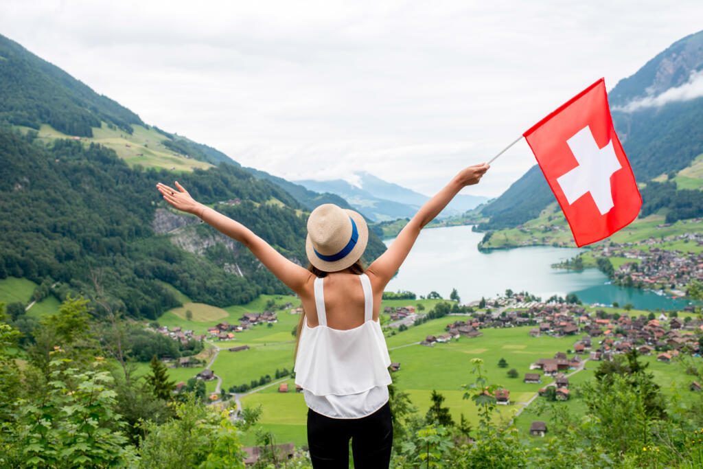 Une femme porte le drapeau suisse face à un paysage