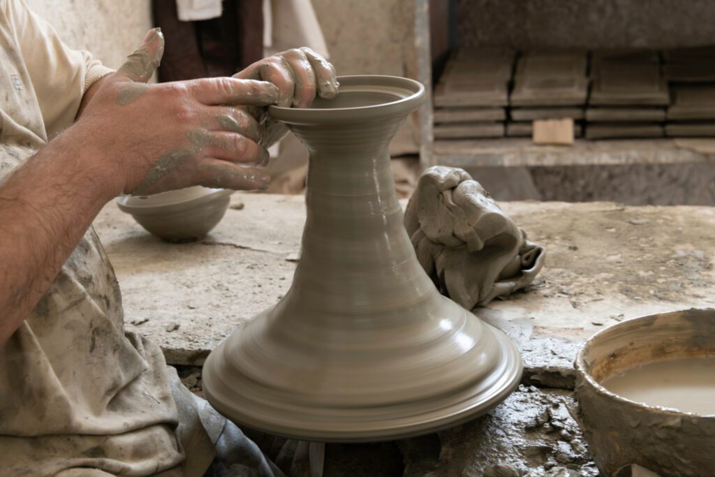 Close-up hands using pottery wheel making large ceramic vase