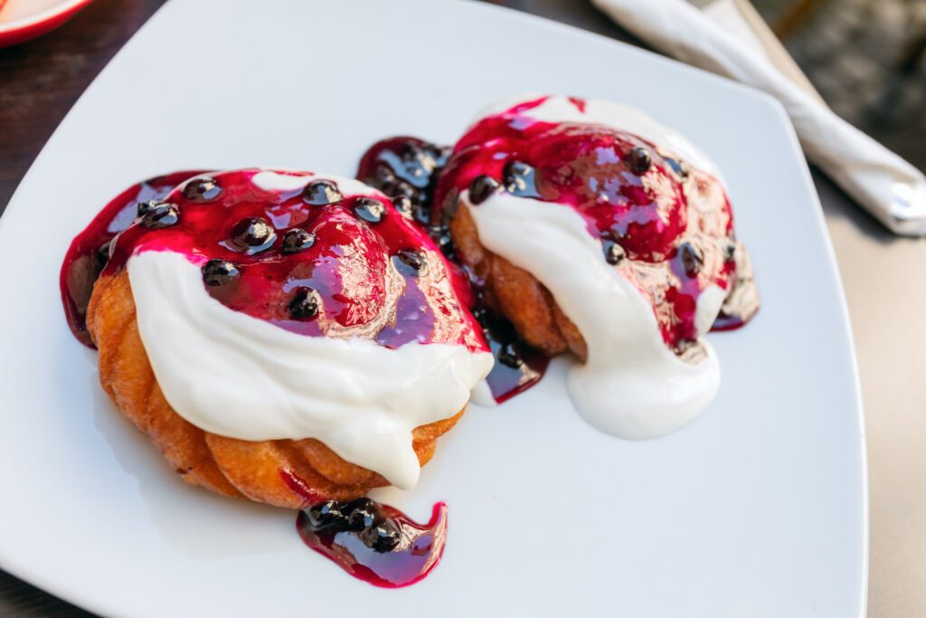 A close up of two portions of taditional Papanasi, a popular Romanian dessert.