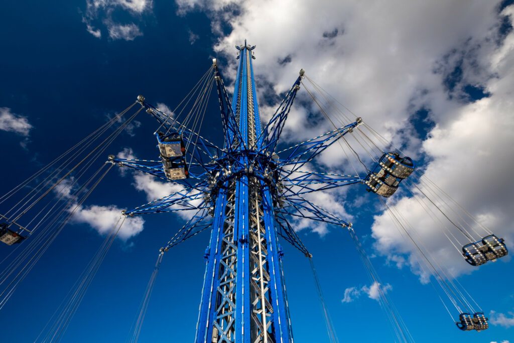 Orlando, Florida, US - February 2019: Orlando Starflyer is the tallest swing ride standing at 450 feet. All double seats are empty on this safety test run. The structure is blue with silver seats.