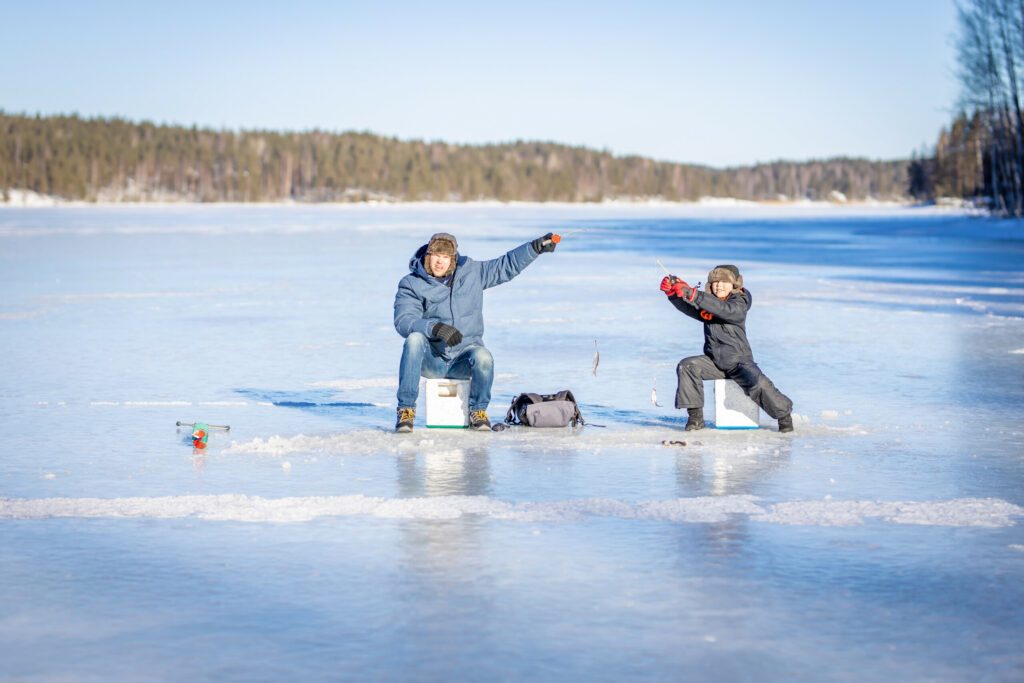 Father and son at winter fishing on frozen lake