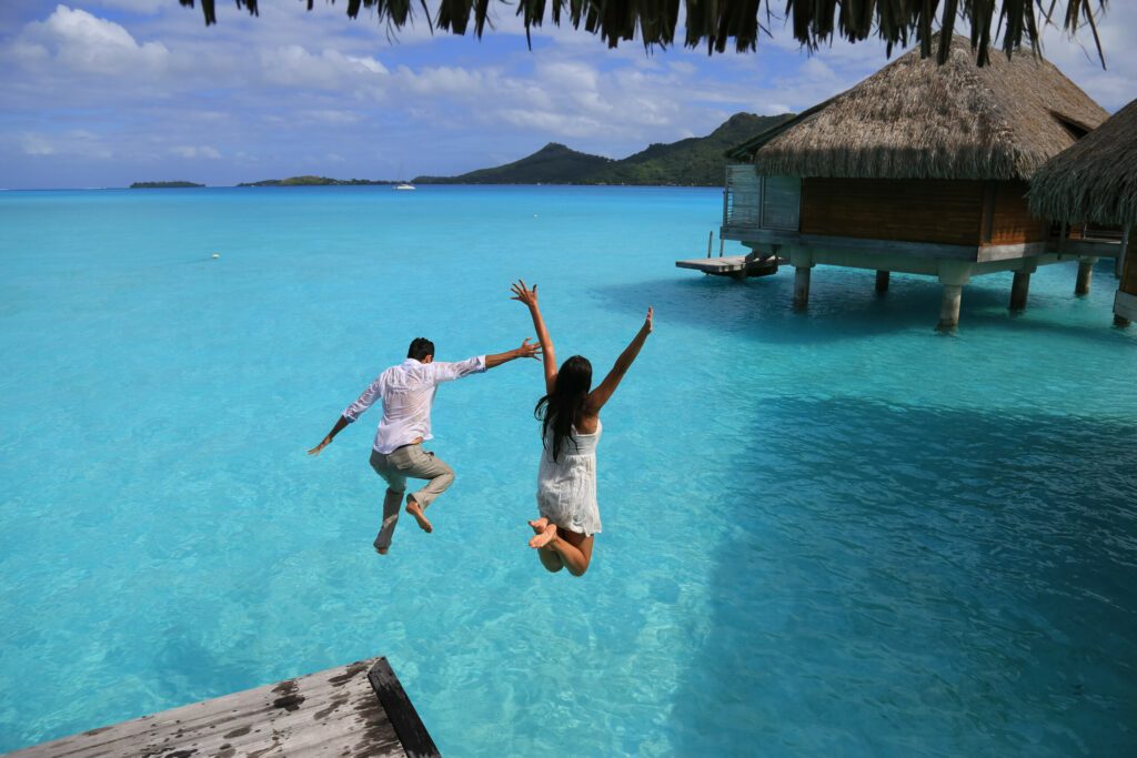 Happiness jump of young couple on the water. Over water bungalows at Bora Bora, French Polynesia.