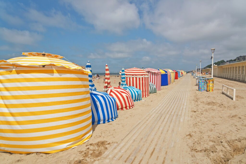 Colored umbrellas at the beach of Deauville with blue cloud sky.