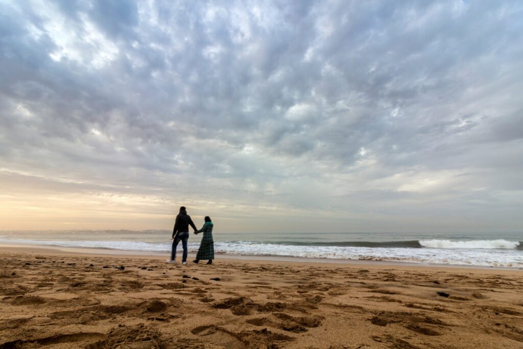 Couple walking at Sunset in Dar Bouazza beach, in Tamarist