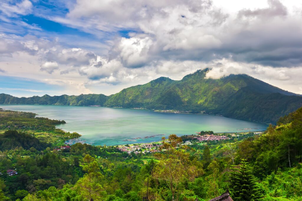 Panoramic view of a lake surrounded by mountain, tropical landscape with colorful clouds in the sky. Fisheries and settlements on the shore. Danau Batur, Gunung Batur, Kintamani, Bali, Indonesia.