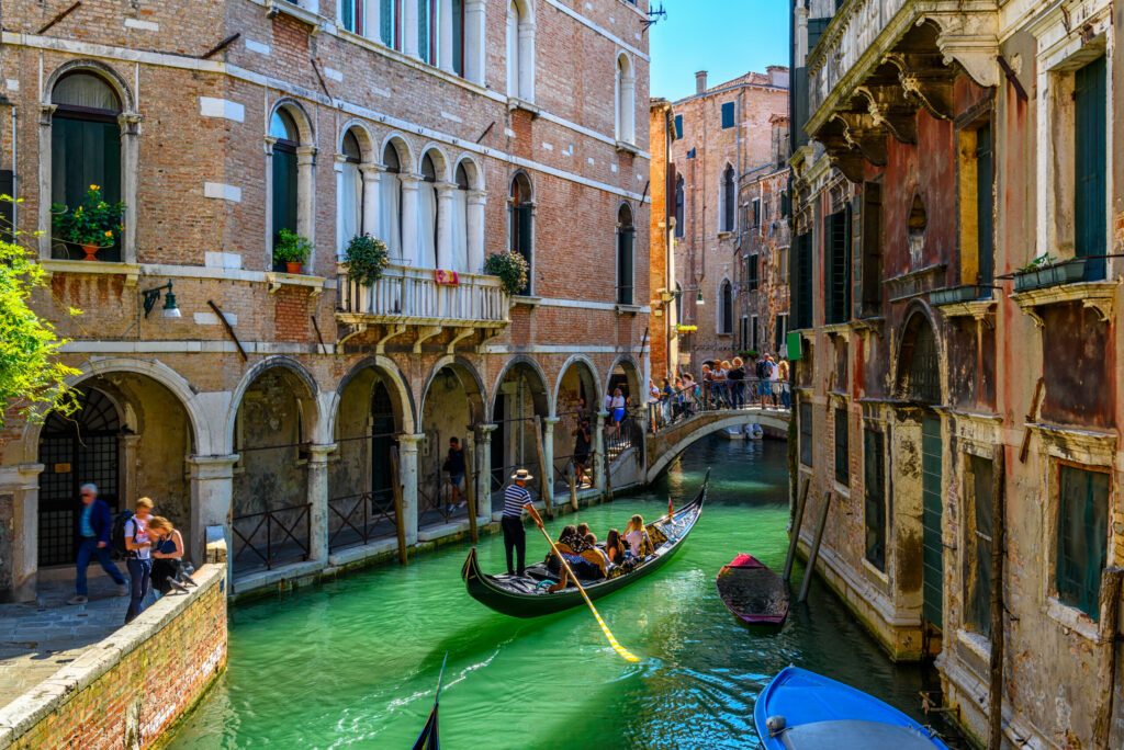 Narrow canal with gondola and bridge in Venice, Italy. Architecture and landmark of Venice. Cozy cityscape of Venice.