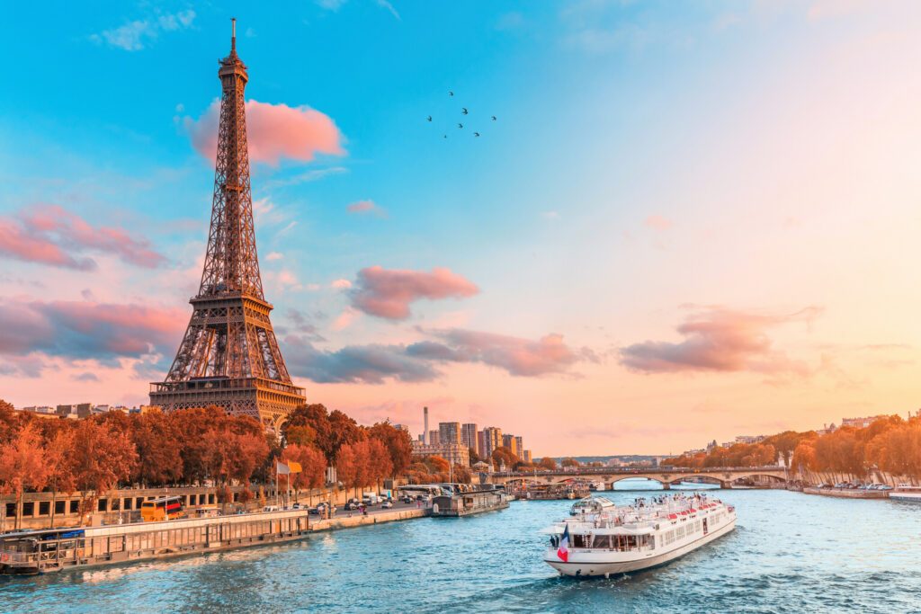 The main attraction of Paris and all of Europe is the Eiffel tower in the rays of the setting sun on the bank of Seine river with cruise tourist ships