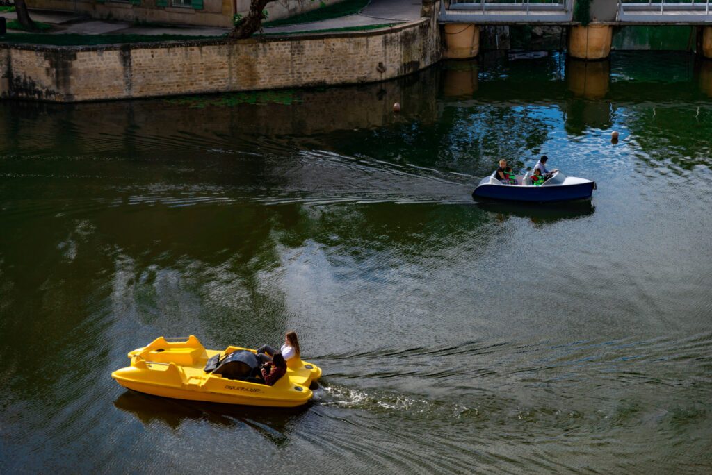 Deux petites embarcations (bateau et pédalo) de plaisance se croisant sur le fleuve de la Moselle