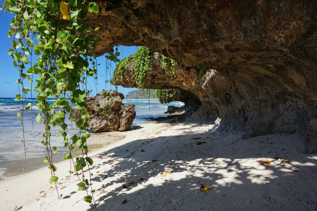 Small sandy beach with vines hang down from the rocks on the sea shore, Rurutu island, south Pacific ocean, Austral archipelago, French Polynesia