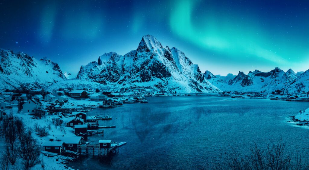 Wonderful snowy winter in Norway. Beautiful night with aurora borealis, in amazing winter landscape of the Lofoten Islands. Snow-covered riverbed and mountains under Northern lights. Creative image.