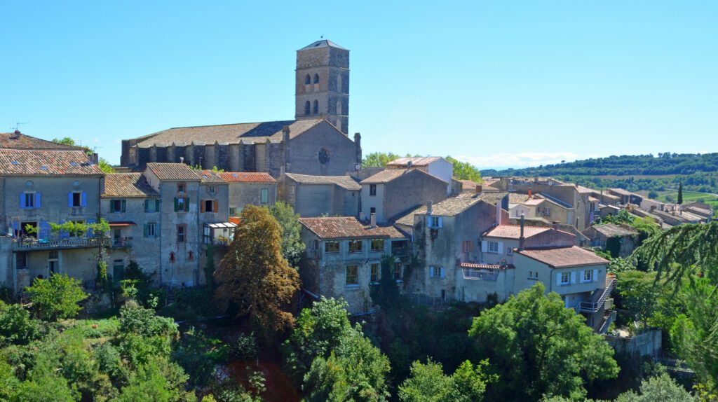 A view of the village of Montolieu Aude  Languedoc - Roussillon  France. Trees valley ancient houses and church bell tower.