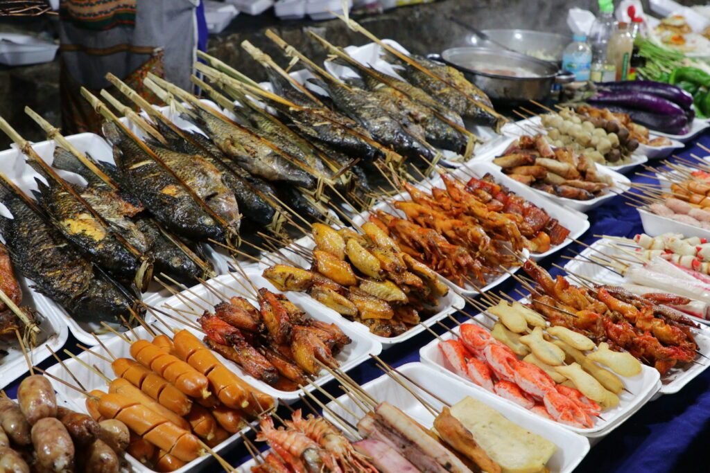 Grilled fish and meat skewers sold in an Asian food street market