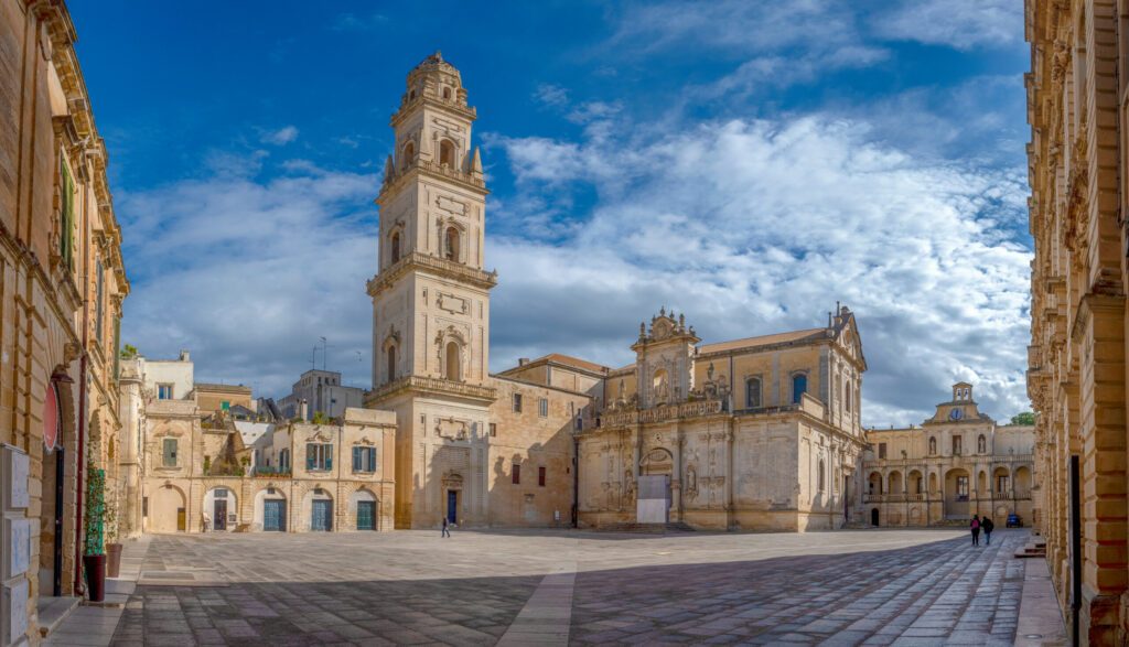 Panorama of Piazza del Duomo square , Campanile tower and Virgin Mary Cathedral ( Basilica di Santa Maria Assunta in Cielo ) , Caritas Diocesana in Lecce - Puglia, Italy. Baroque city of Apulia