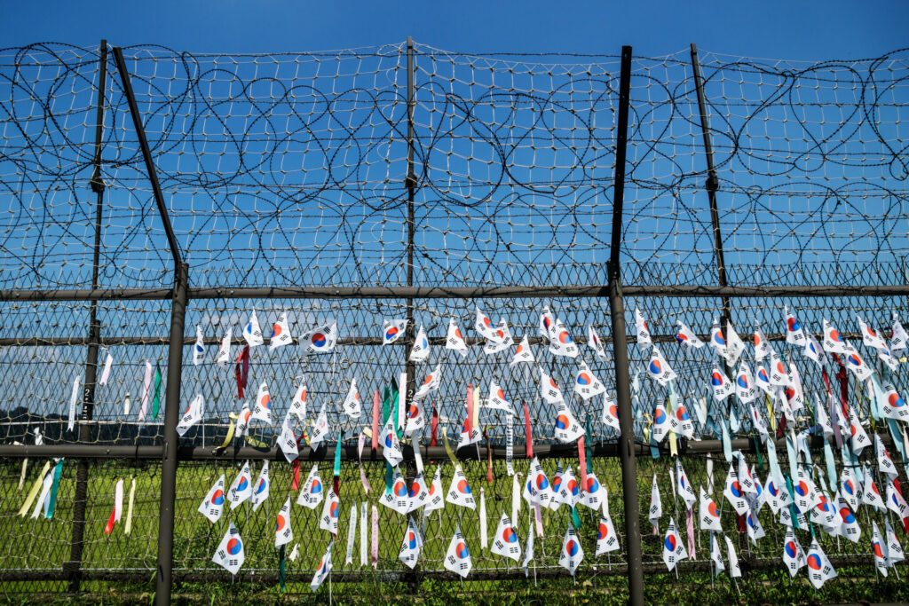 Fence with barbed wire and south korean flags at the demilitarised zone DMZ at the freedom bridge with blue sky, South Korea, Asia