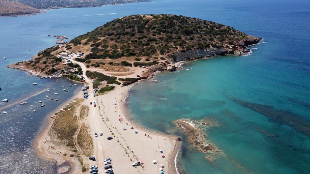 Aerial drone bird's eye view of iconic beach and small islet of Agios Nikolaos, Anavysos, Athens Riviera, Attica, Greece