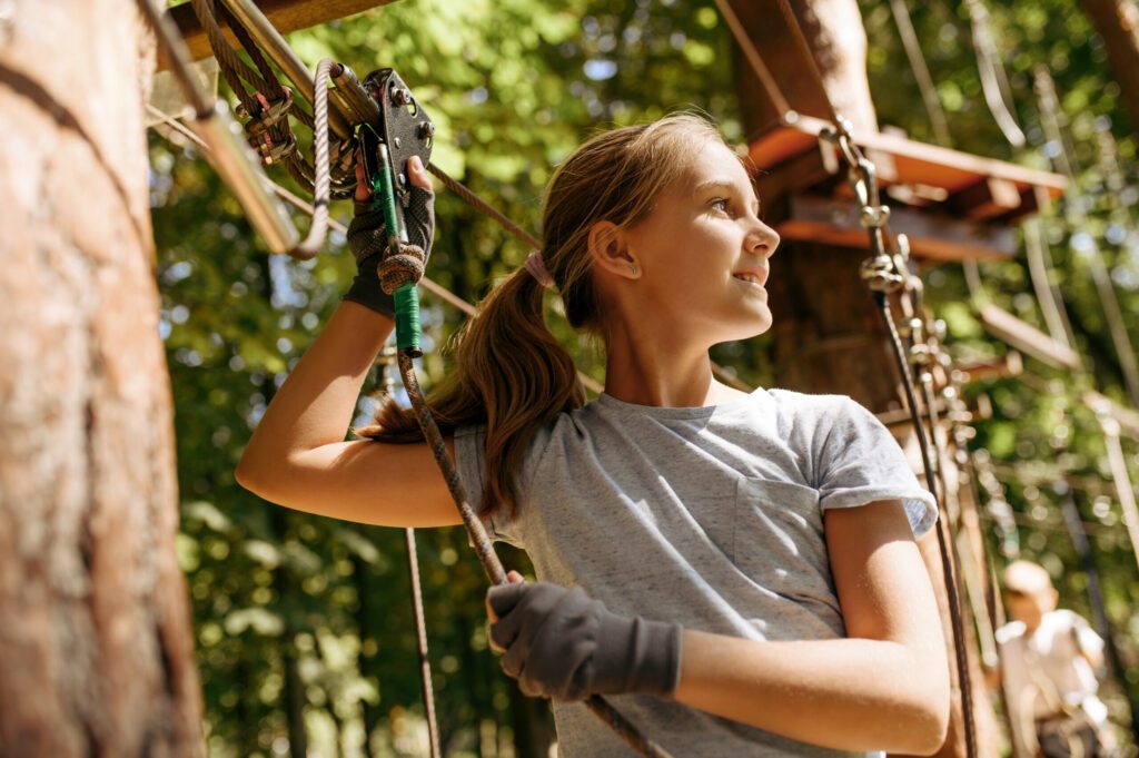 Little girl leisures in rope park, playground