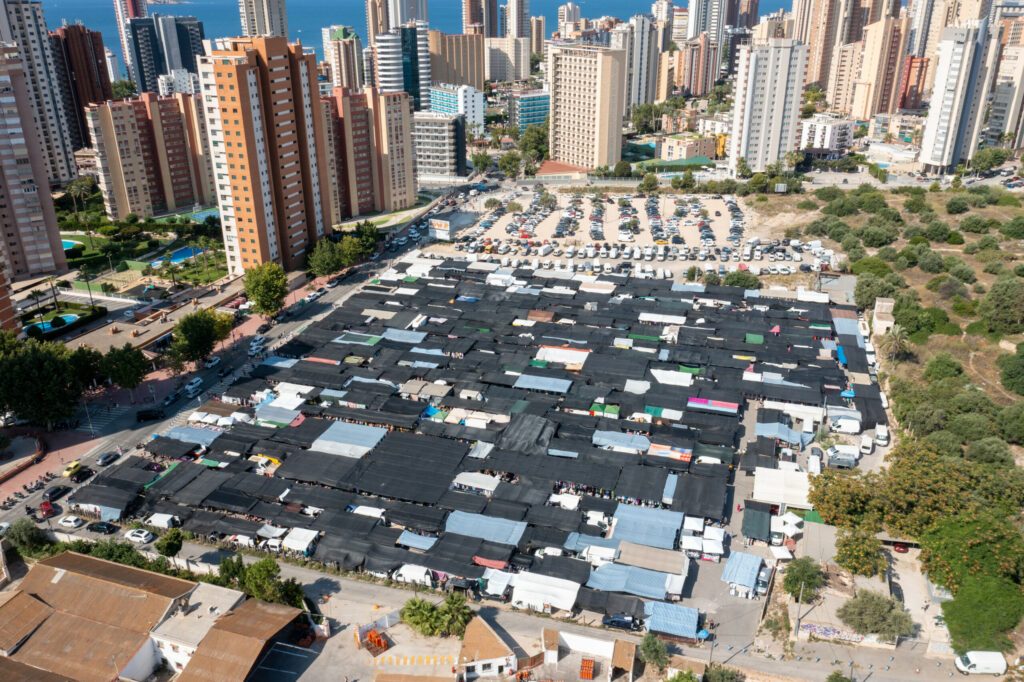 Aerial drone photo of the city of Benidorm in Spain in the summer time showing the famous market and market stalls with the car park and busy road along side the markets