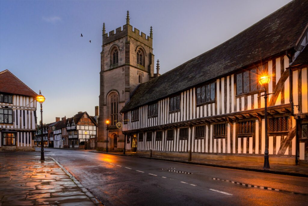 Stratford upon Avon, Guildhall and chapel with church. Street lights shine on timber framed buildings