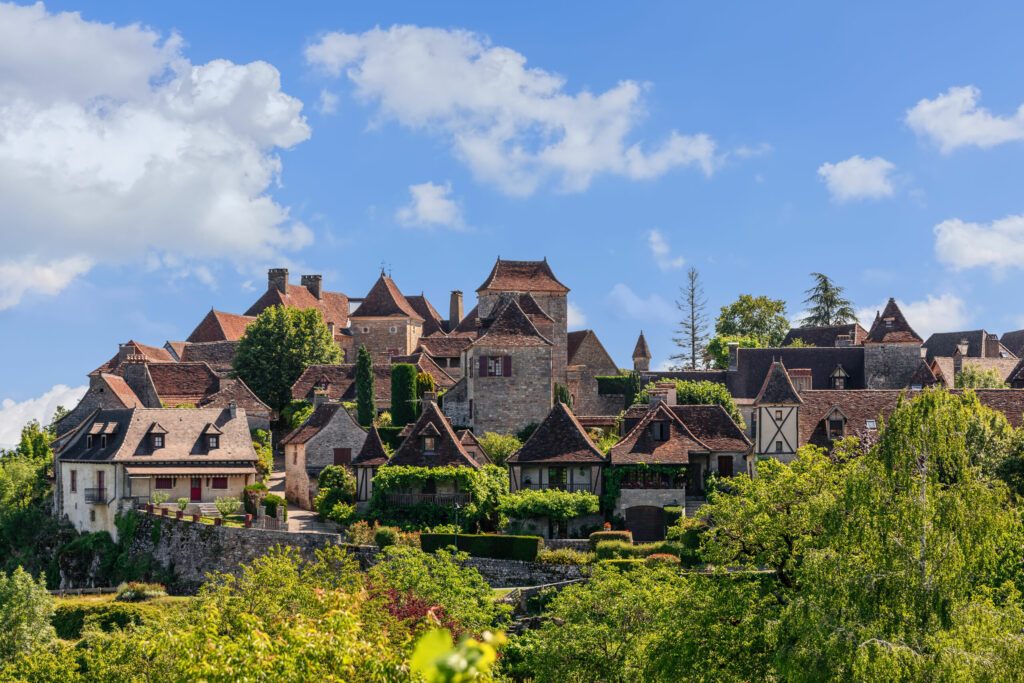 Panoramic view of toy small medieval Loubressac village with stone houses with sloping roofs surrounded by lush vegetation. Lot, Occitania, France