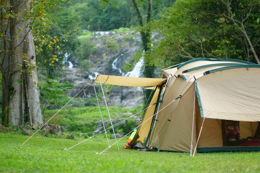 camping tent on waterfall and stream with tree in green jungle or forest for summer winter holiday relax and vacation travel trip with trekking and picnic on meadow grass at Khlong Nam Lai Waterfall