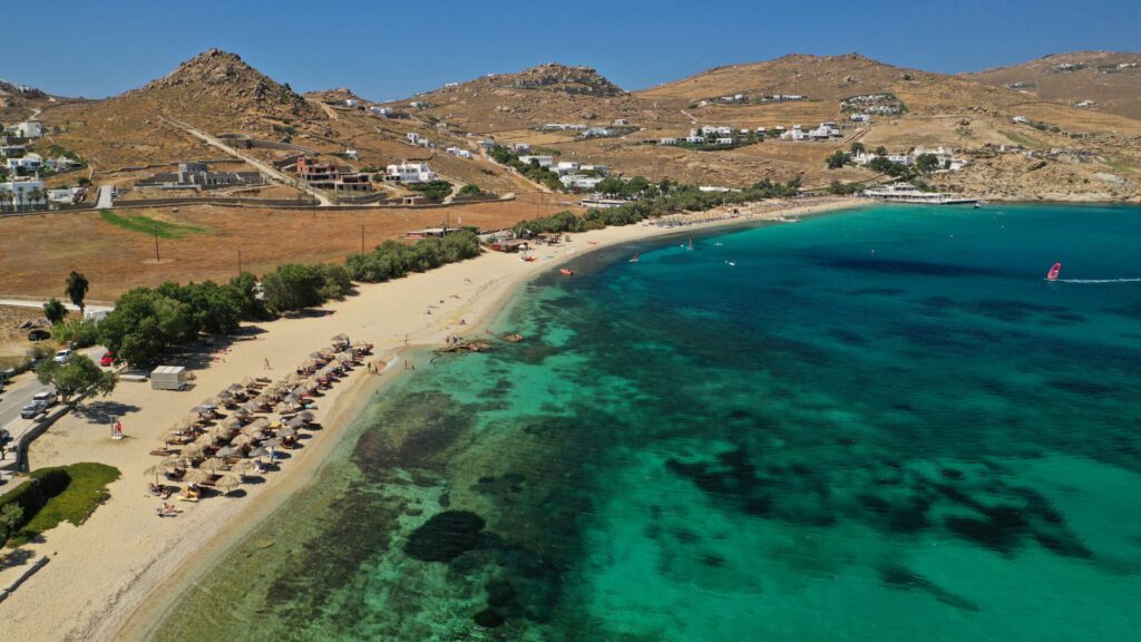 Aerial drone photo of famous organised with sun beds and umbrellas beach of Kalo Livadi with emerald clear sandy sea shore, Mykonos island, Cyclades, Greece