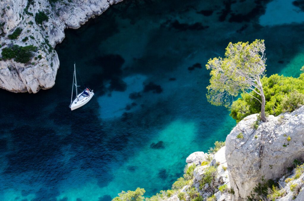 Tree overhanging a sailboat in the Calanque En-Vau near Cassis and Marseille