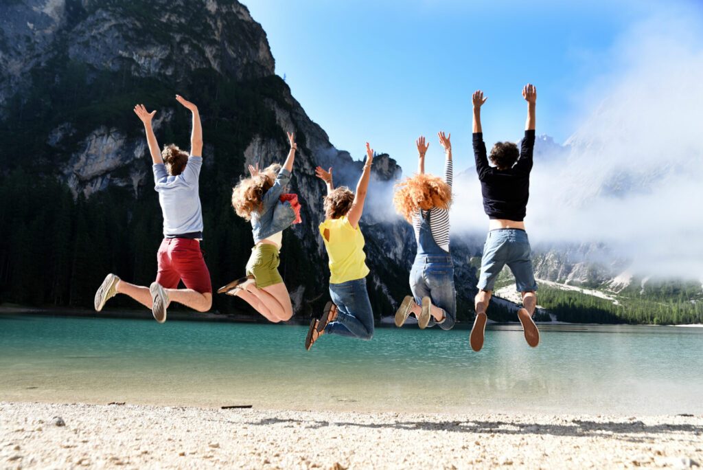 Group of friends of different nationalities on vacation on a mountain lake in the middle of nature, take pictures and celebrate spring or summer