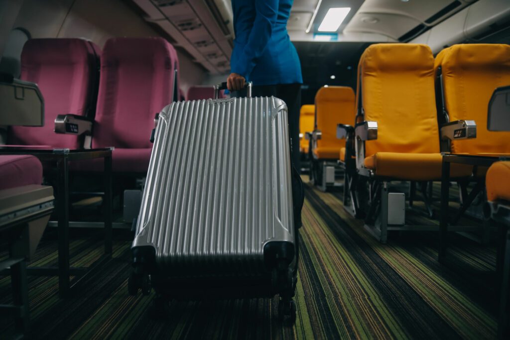 Asian female traveler putting luggage into overhead locker on airplane during boarding.