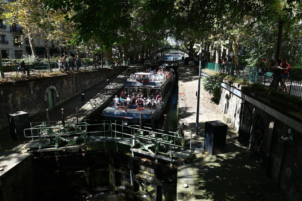 Un bateau touristique attend de passer une écluse sur le canal Saint-Martin à Paris